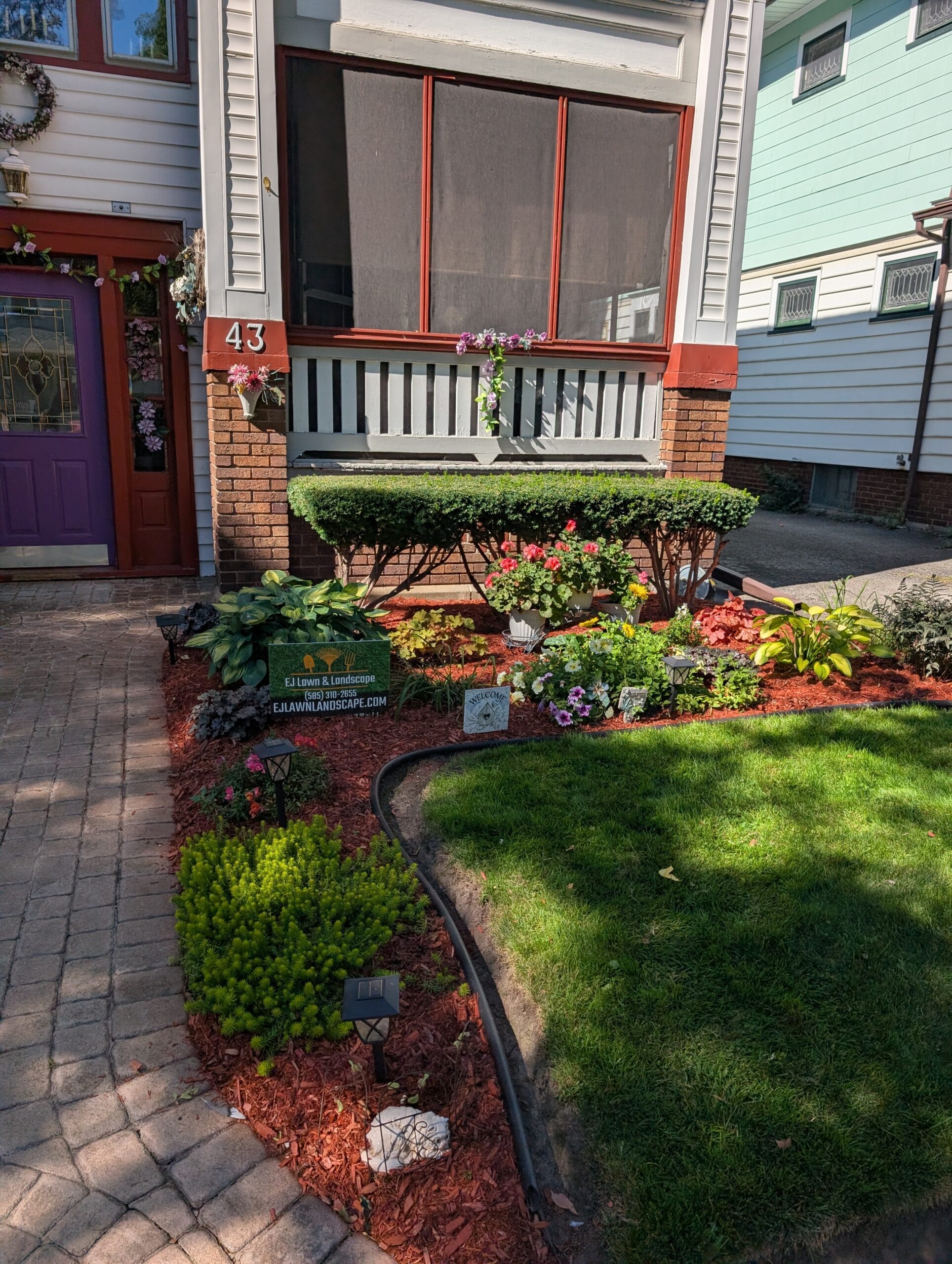 Front yard garden featuring a bonsai-style bush and flowering plants, showcasing professional bush and garden maintenance by EJ Lawn & Landscape in Rochester, NY