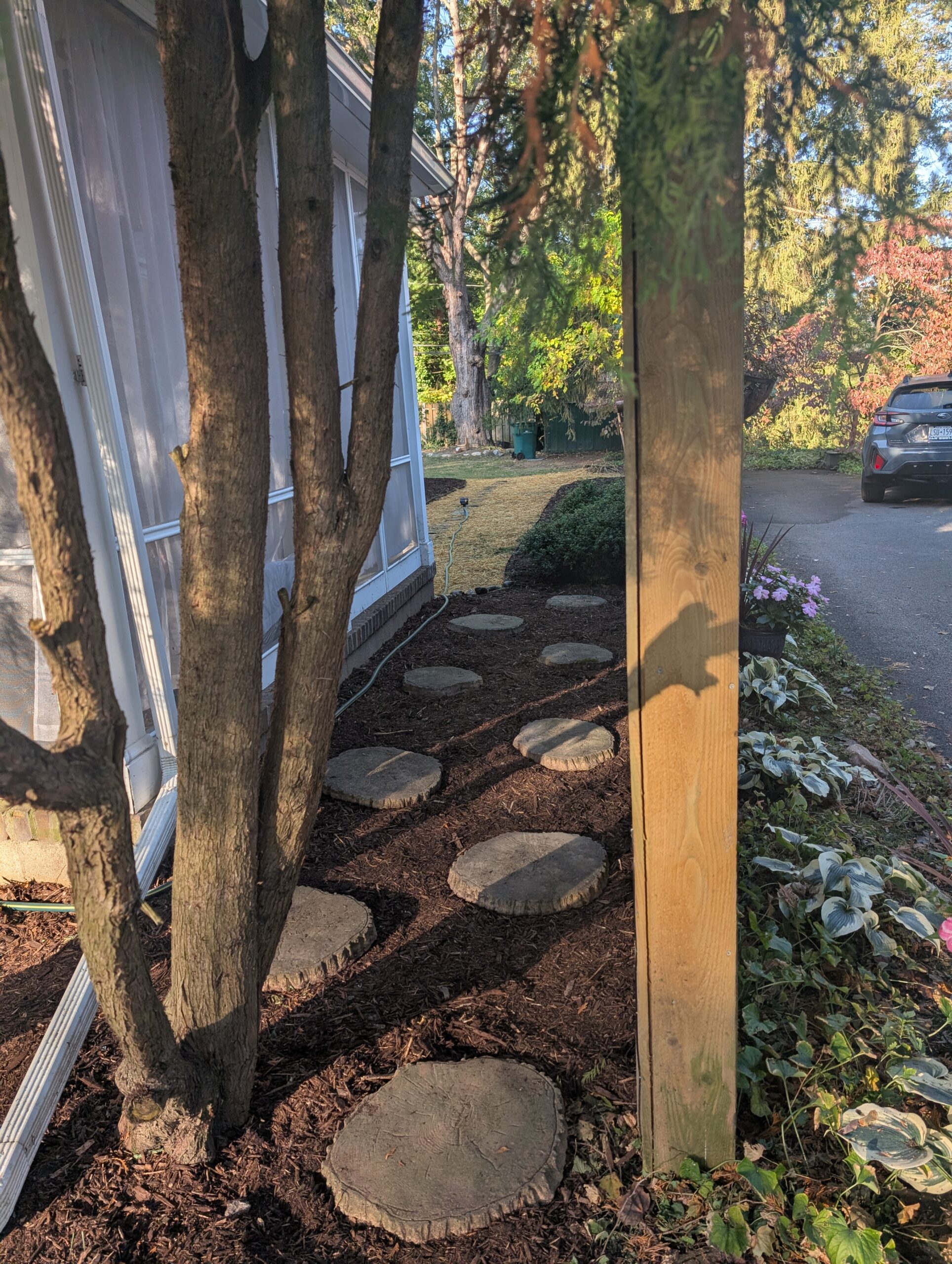 Stone stepstones placed in mulch beside a house in Brighton, showcasing professional hardscaping services by EJ Lawn & Landscape