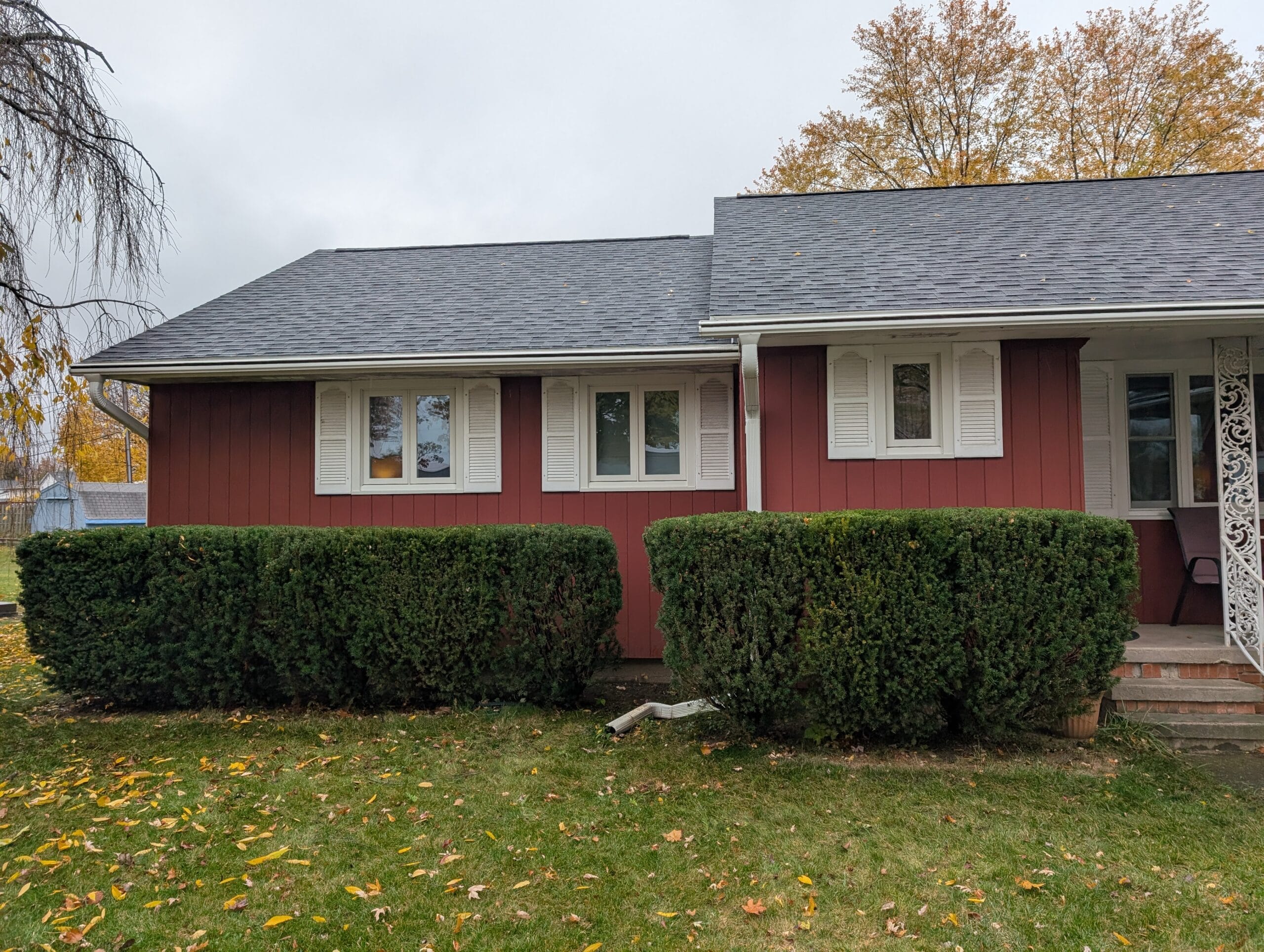 Freshly trimmed bushes in front of a red house after professional garden maintenance in Rochester NY