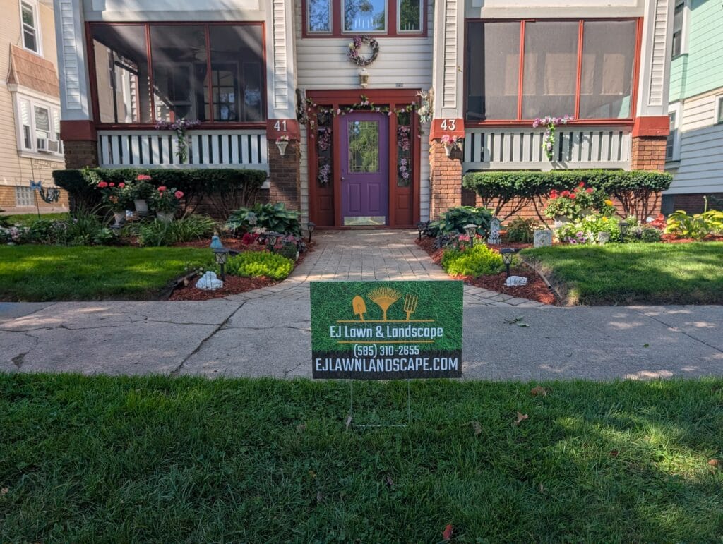 Close-up of front garden beds with EJ Lawn and Landscape sign in Rochester NY