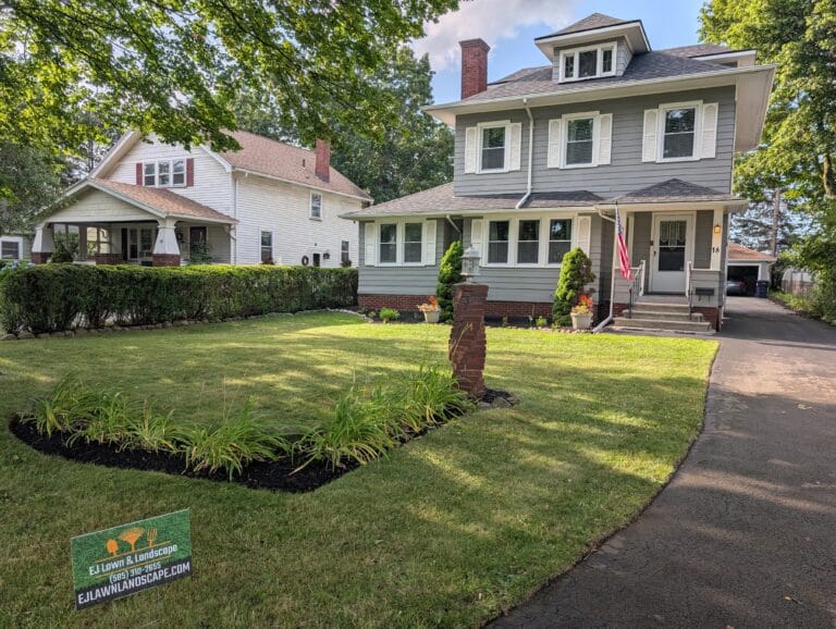 Freshly mowed front lawn with EJ Lawn and Landscape sign in Irondequoit NY