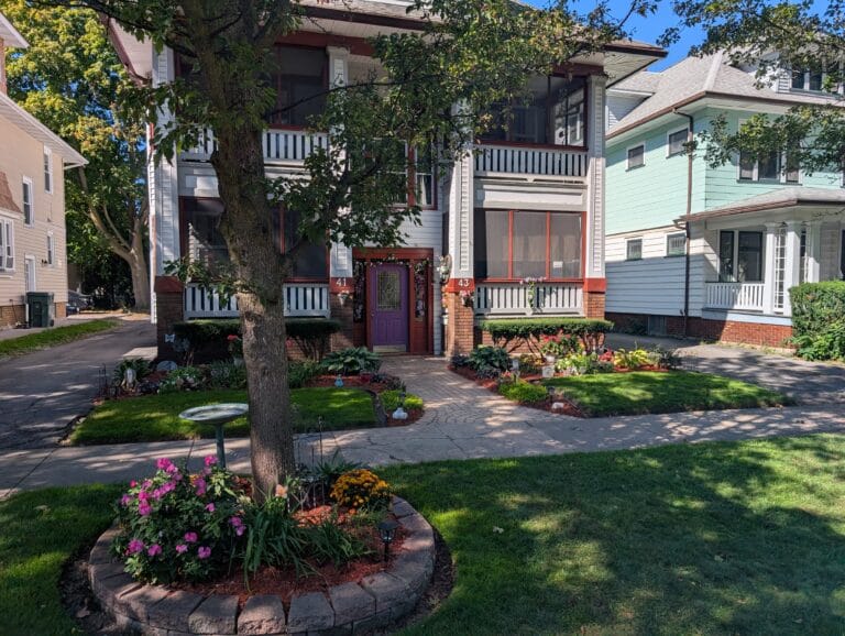 Full view of front yard with multiple gardens around house and trees in Rochester NY