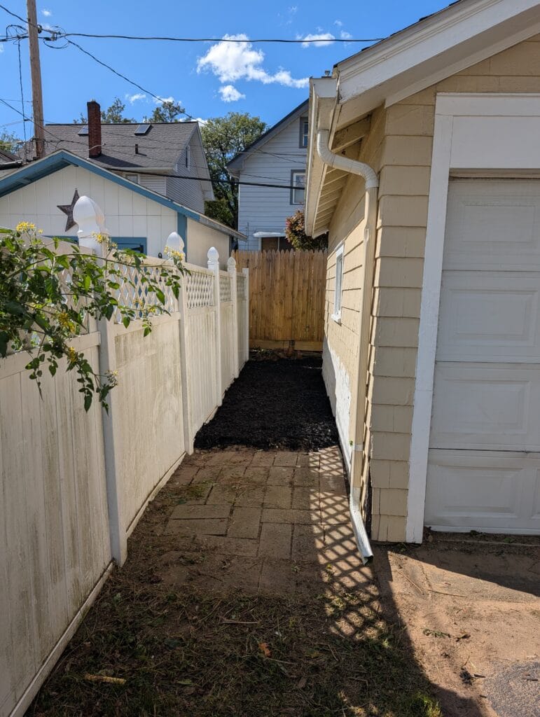 Garage side cleared with mulch after yard cleanup in Rochester NY