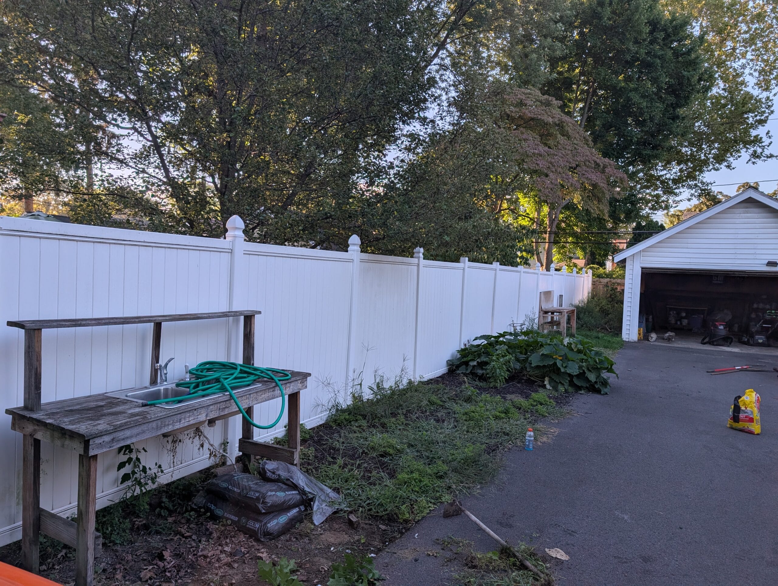 Yard and garage area with junk and overgrowth before cleanup in Irondequoit NY