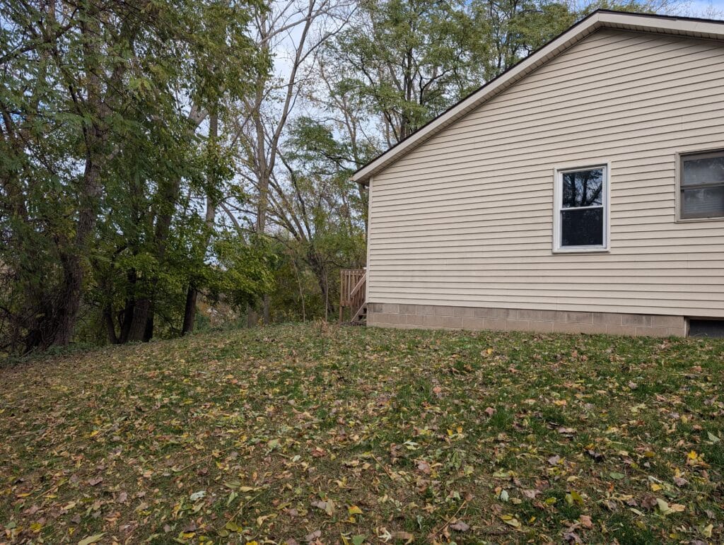 Side yard covered in fallen leaves before cleanup in Irondequoit NY
