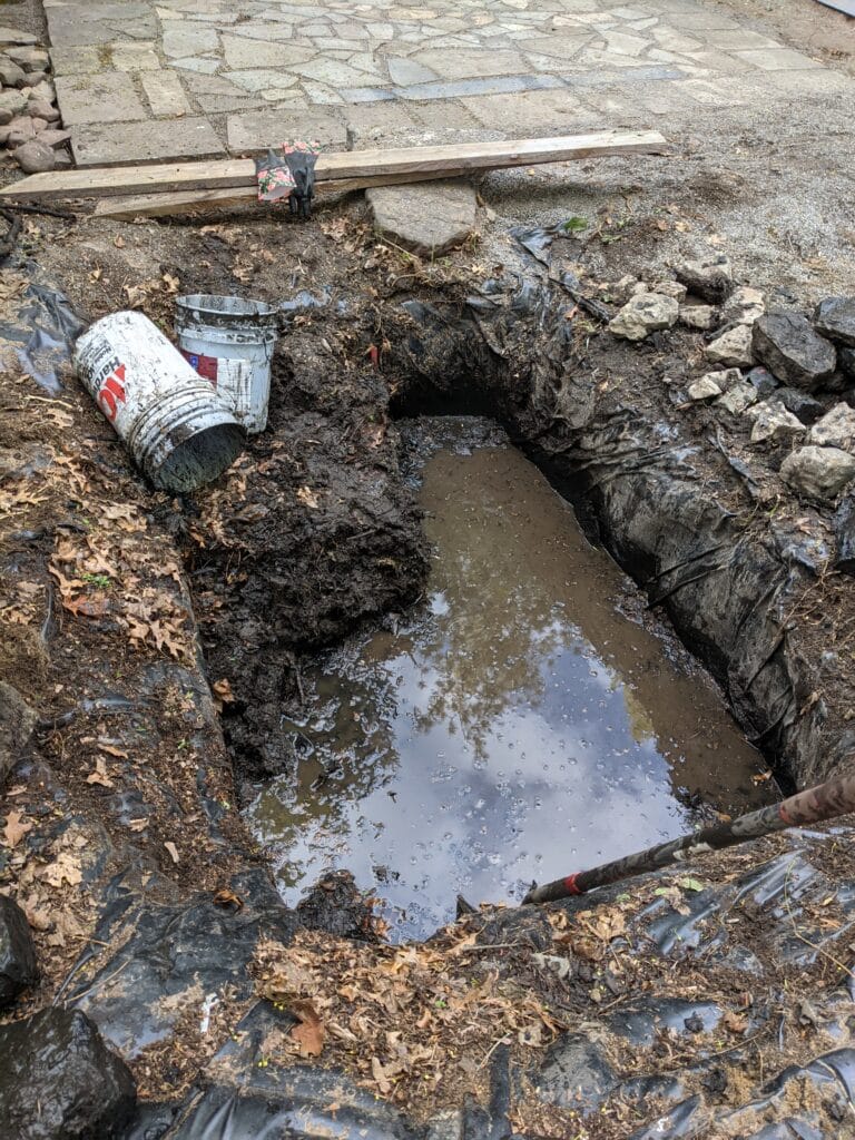 Partially cleaned pond with remaining water and debris being prepared for filling in Irondequoit.