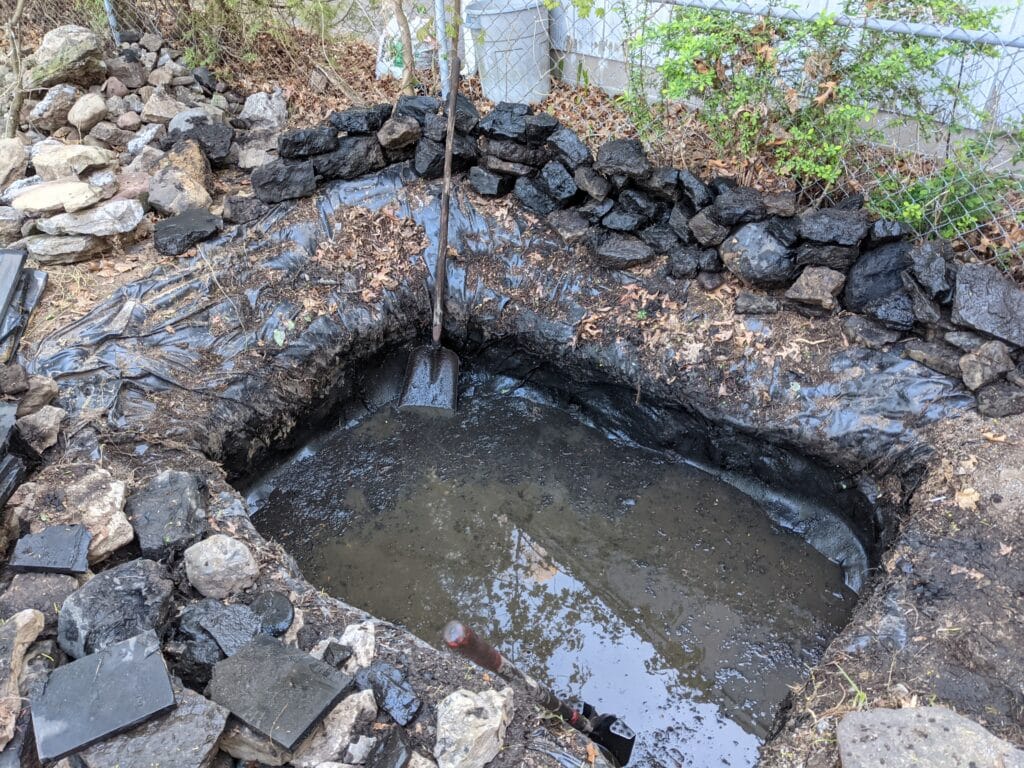 Cleared pond with rocks stacked around the perimeter in Irondequoit, ready for filling.