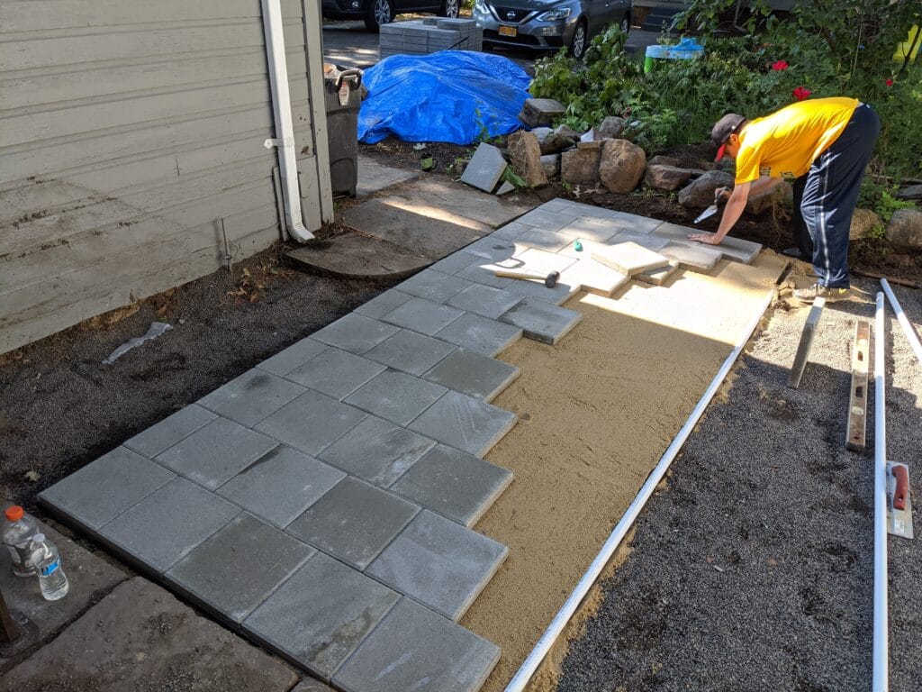 Paver stones being laid over filled pond area in Irondequoit for patio installation.