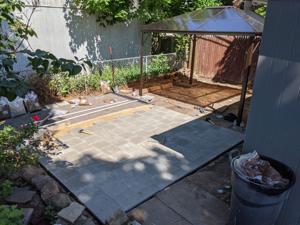 Paver patio in progress in Irondequoit, half the stones laid and aligned.