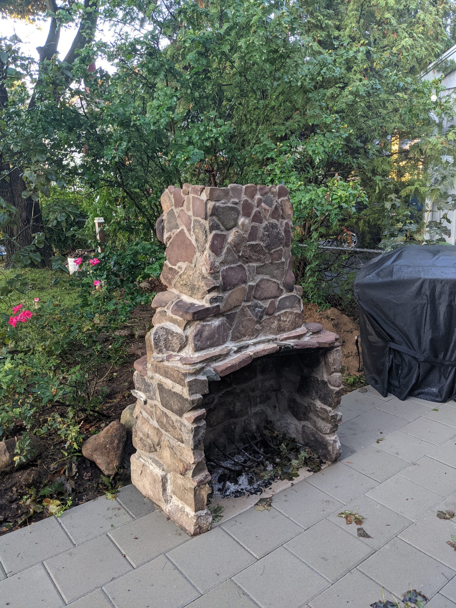 Completed stone fireplace in Irondequoit built with reclaimed pond rocks at the edge of a patio.