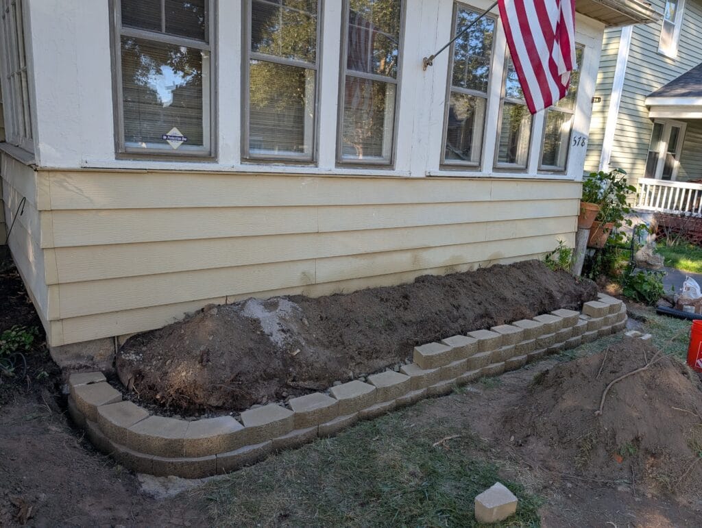 Stone retaining wall halfway installed in front yard in Rochester NY