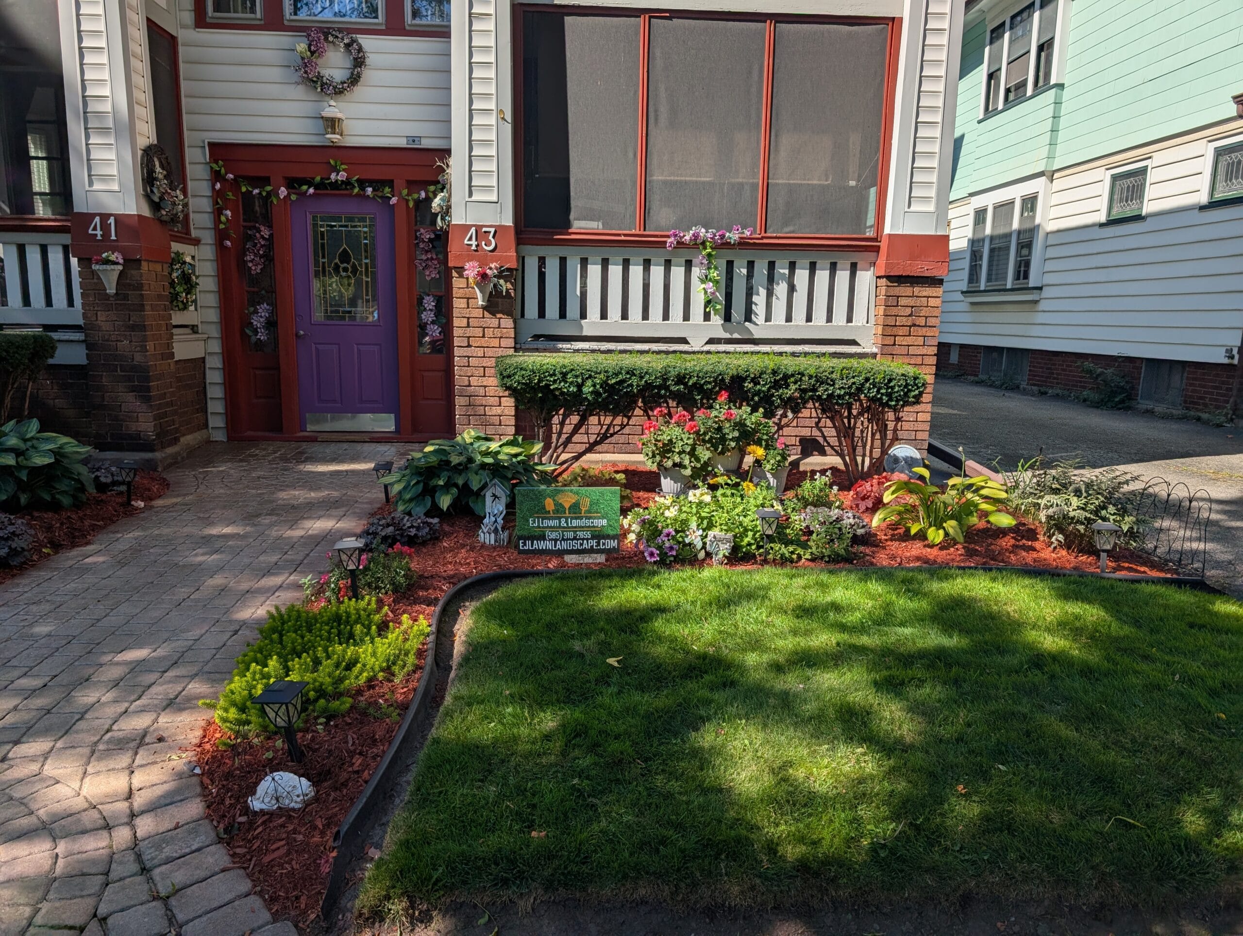 Close-up of right side front garden with EJ Lawn and Landscape sign in Rochester NY