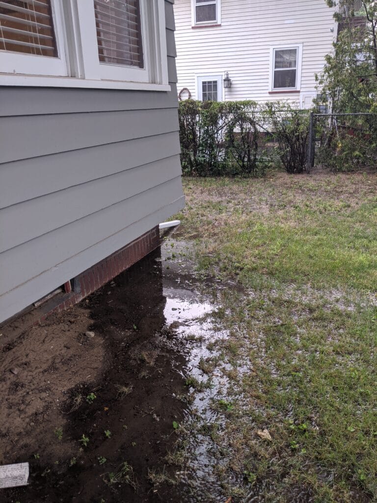 Water pooling near the foundation of a home before regrading in Irondequoit NY
