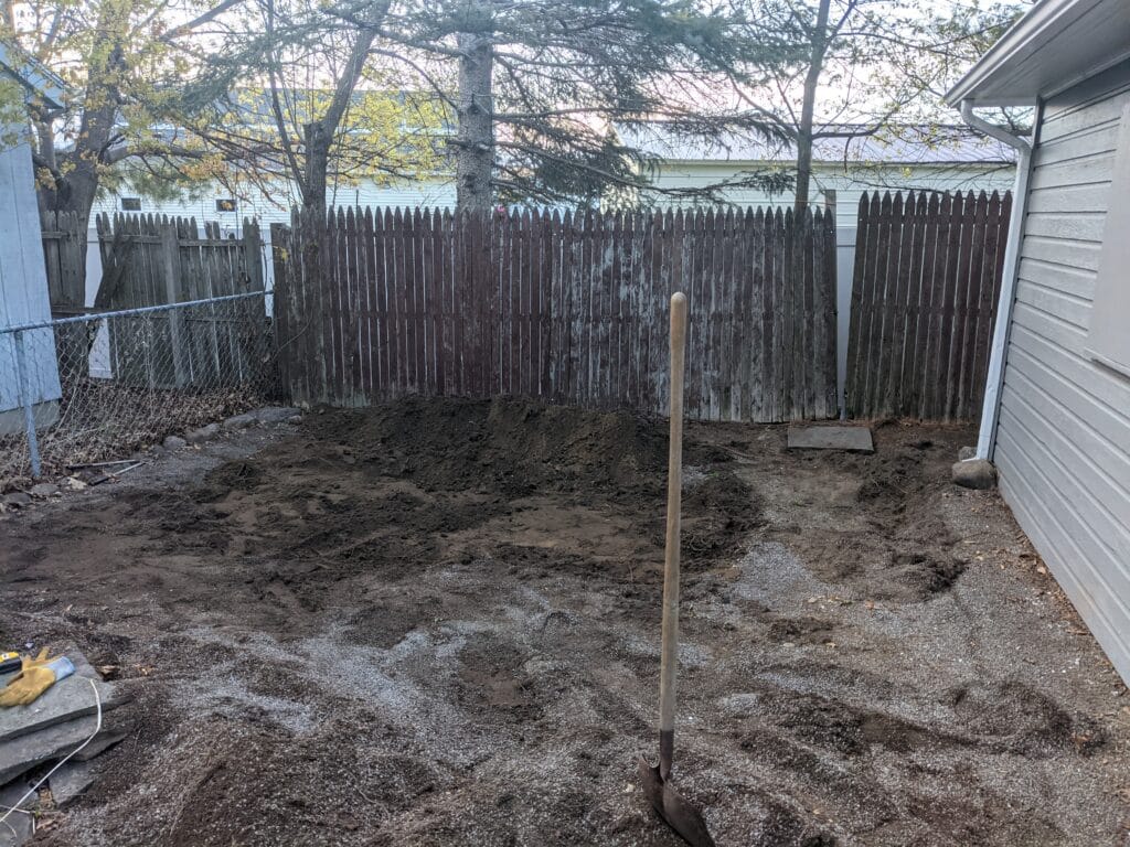 Unleveled dirt area before natural stone patio installation in Irondequoit, showing cleared space ready for construction.