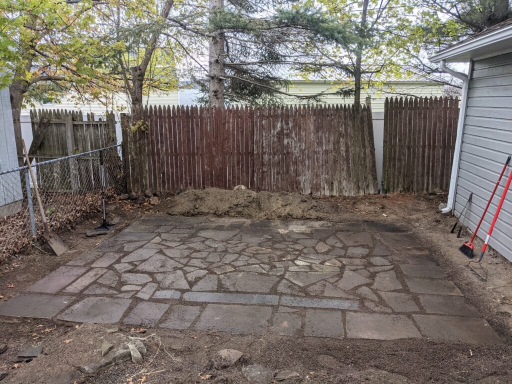 Alternate view of the completed natural stone patio in Irondequoit, showing the flowing layout and craftsmanship.