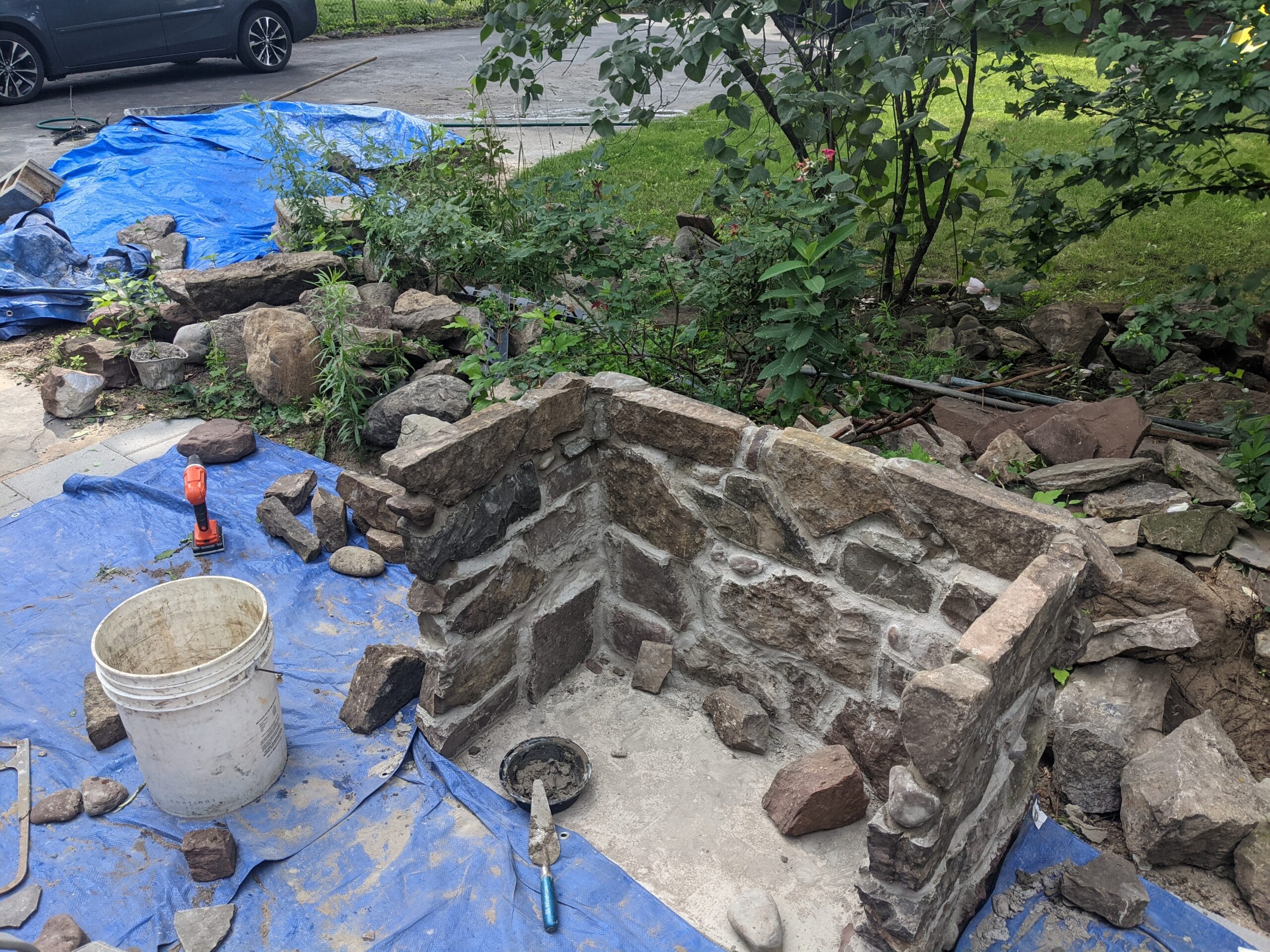 Stone fireplace halfway built in Irondequoit, showing hand-stacked rocks during construction.