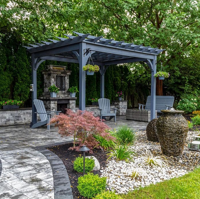 Stone patio with pergola and landscaped garden bed in a residential backyard in Rochester