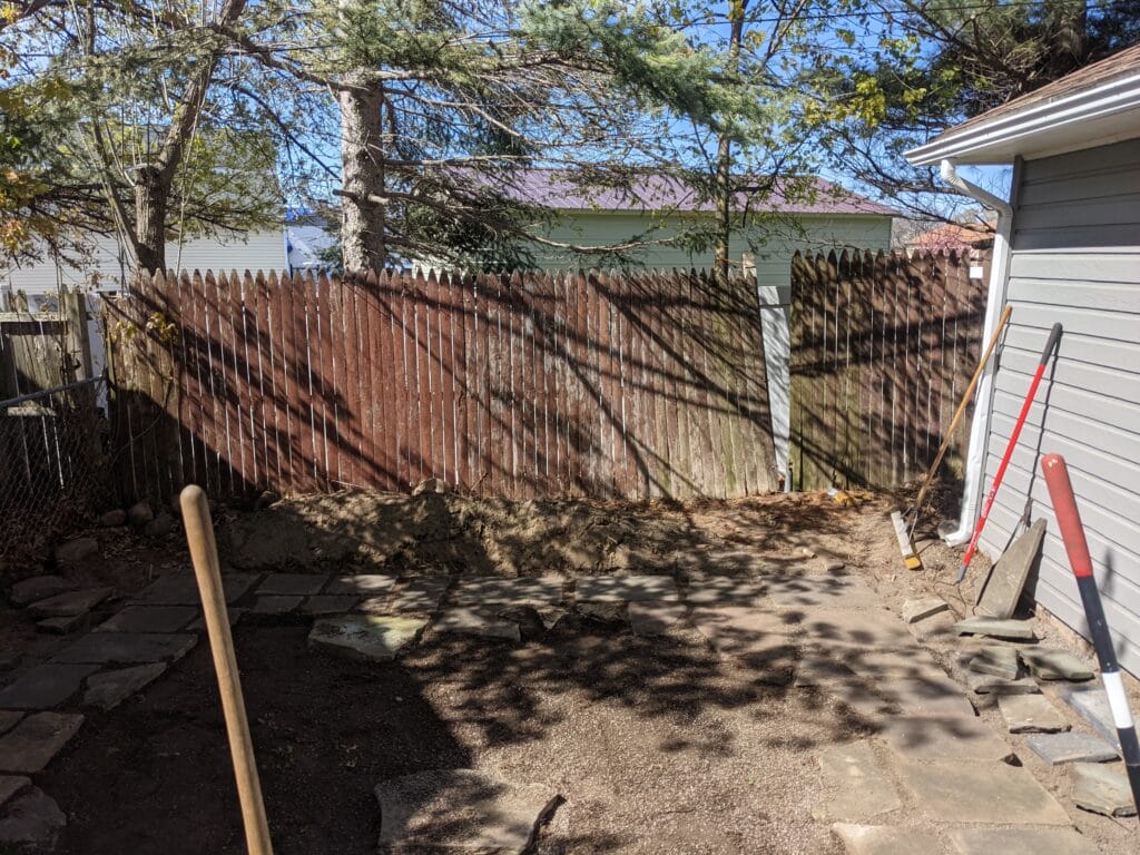 Natural stones being hand-arranged for patio installation in Irondequoit, showing the layout process.